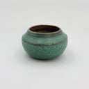 Green ceramic pot with brown rim on a white background