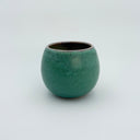 Green ceramic vase on a light gray background