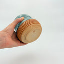 Hand holding a cylindrical object with marbled design and wooden texture on a white background