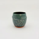 Green ceramic cup with decorative patterns on a white background