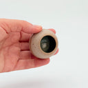 Hand holding a Kleybird Strata mini vase with striped clay bands and pale aqua interior.