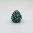 Kleybird Dotty bud vase with blue glaze and raised texture held in the palm of a hand.
