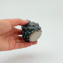 Hand holding a Kleybird Dotty bud vase with blue glaze and raised texture.