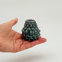 Hand holding a Kleybird Dotty bud vase with blue glaze and raised texture.