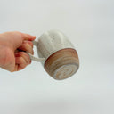Kleybird Strata mug held in hand, showing marbled clay bottom and white speckled glaze top.