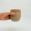 Kleybird Strata handleless tumbler with marbled clay exterior and light aqua interior held in hand.