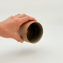 Kleybird Strata handleless tumbler with marbled clay exterior and light aqua interior held in hand.