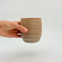 Kleybird Strata handleless tumbler with marbled clay exterior and light aqua interior held in hand.