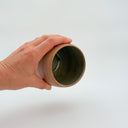Kleybird Strata handleless tumbler with marbled clay exterior and light aqua interior held in hand.