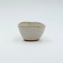 Small triangular ceramic cup with speckled white glaze, shown from a top-down view to highlight the geometric rim.