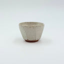 Small faceted ceramic sake cup with speckled white glaze, held in a hand to show the 100ml scale.