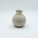 Textured white ceramic jug with a small pour spout and birch-like glaze, held in a hand to show the 325ml scale.