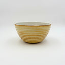 Large weighted stoneware bowl with yellow and golden brown ribbed exterior and white glazed interior, hand-thrown in Boulder CO.