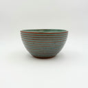 Hand-thrown stoneware bowl with a ribbed exterior of raw golden-brown clay and soft turquoise interior